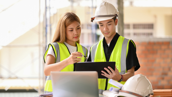 Two construction workers looking at a tablet. 