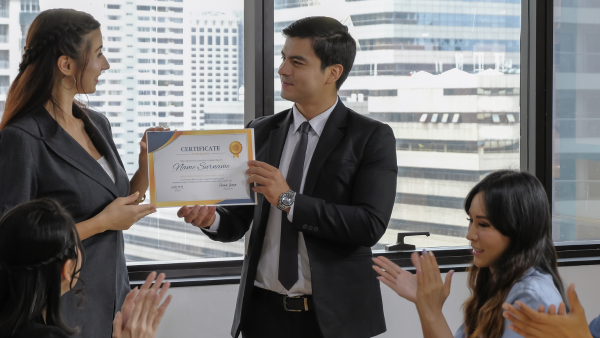 A man awarding his colleague a certificate. 